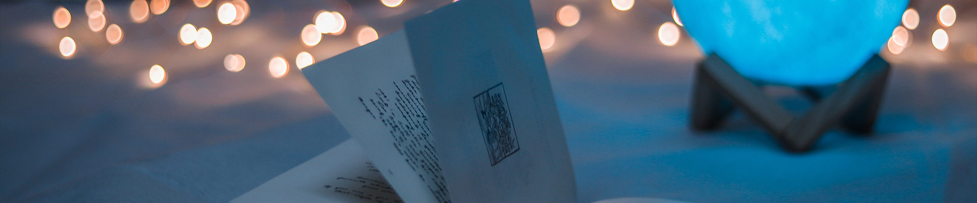 Close-up of a folded letter on a blue surface with warm bokeh lights and a blue glowing orb on a stand.